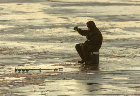 Lipetsk, Russia - December 6, 2019: A man catches fish on ice in the morning at the Matyr reservoir.のeditorial素材