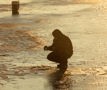 Lipetsk, Russia - December 6, 2019: A man catches fish on ice in the morning at the Matyr reservoir.のeditorial素材