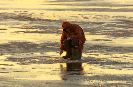 Lipetsk, Russia - December 6, 2019: A man catches fish on ice in the morning at the Matyr reservoir.のeditorial素材