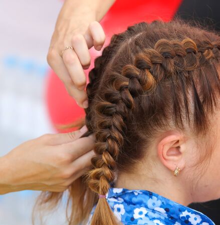 Braiding braids on the head of a girl in the salon.