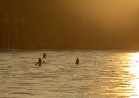 Fishermen fish on ice at dawn.の写真素材