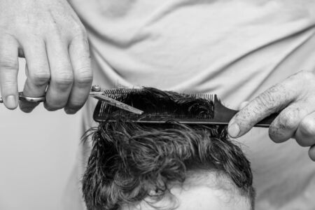 Hairdresser cuts the hair of a boy with scissors.の写真素材