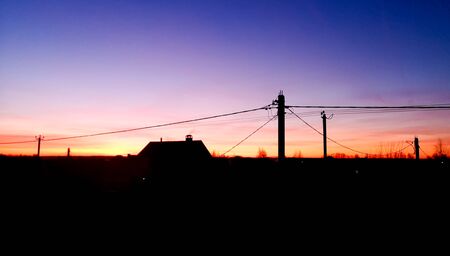 Electric wires against the background of the dawn of the sun.の写真素材