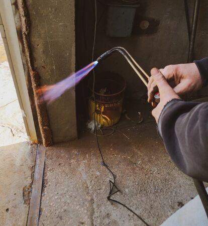 Worker working with gas welding cuts metal.