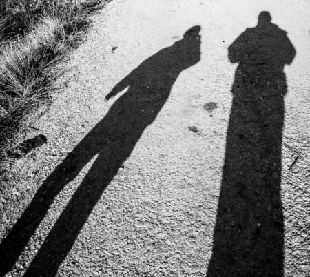 Shadow of two people on the road.