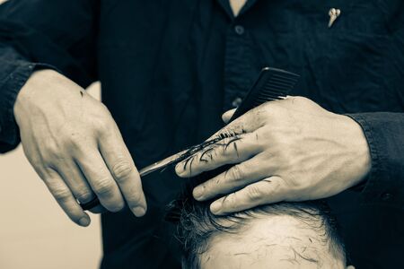 Hairdresser cuts the hair of a boy with scissors.の写真素材