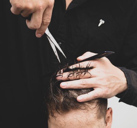 Hairdresser cuts the hair of a boy with scissors.の写真素材