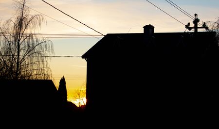 Silhouettes of houses in a cottage village on a background of sunset.の写真素材