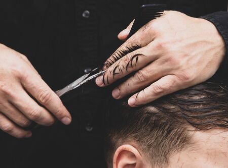 Hairdresser cuts the hair of a boy with scissors.の写真素材