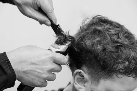 The hairdresser cuts the hair of a boy with a machine.の写真素材