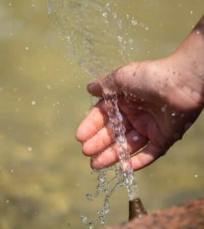 Hand of a girl in the spray of water of the fountain in the summer.の写真素材