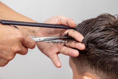 Hairdresser cuts the hair of a boy with scissors.の写真素材