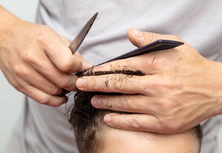 Hairdresser cuts the hair of a boy with scissors.の写真素材