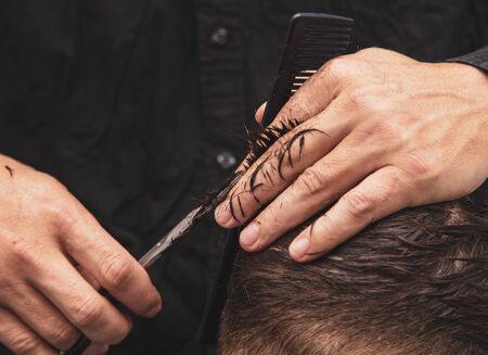 Hairdresser cuts the hair of a boy with scissors.の写真素材