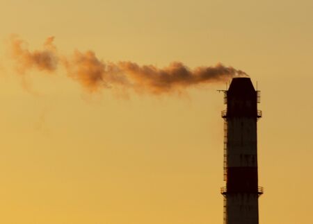 Industrial smoke from a chimney against the backdrop of the dawn of the sun.の写真素材