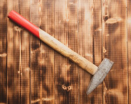 The hammer lies on a wooden background.
