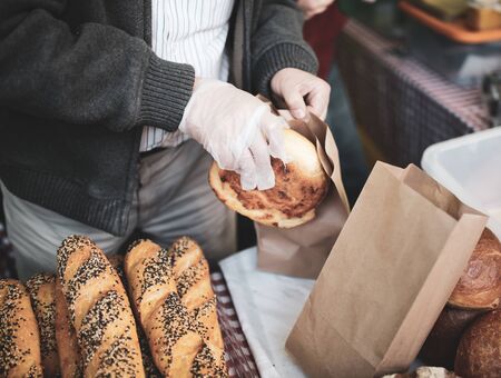 The seller is packing bread in the market.