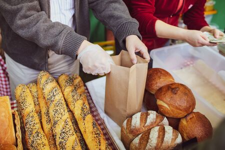 The seller is packing bread in the market.