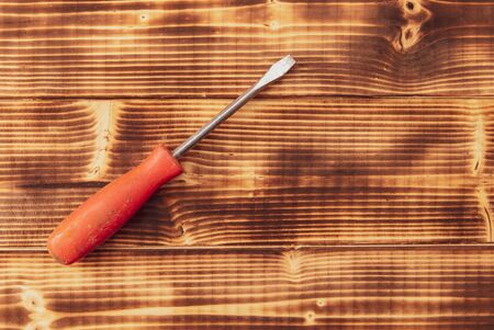 A screwdriver lies on a wooden background.の写真素材