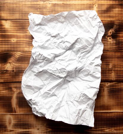 Crumpled white paper on a wooden background.の写真素材