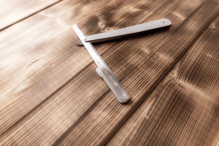 Dangerous razor for haircuts on a wooden background.