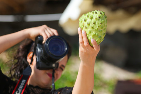 Sanya, Hainan Island, China - January 8, 2020: A girl photographs anon fruit on the beach in Dadonghai Bay.のeditorial素材