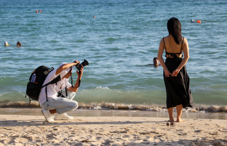 Sanya, Hainan Island, China - January 8, 2020: A man photographs a girl on the beach in Dadonghai Bay.のeditorial素材