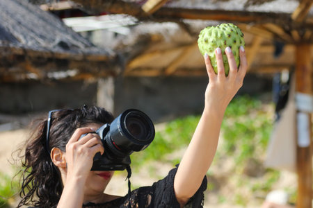 Sanya, Hainan Island, China - January 8, 2020: A girl photographs anon fruit on the beach in...