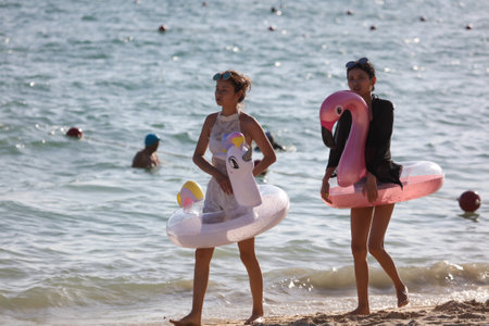 Sanya, Hainan Island, China - January 8, 2020: Girl with flamingo toys on the beach in Dadonghai...