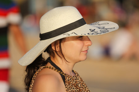 Sanya, Hainan Island, China - January 8, 2020: Girl in a hat with a phone at sunset on the beach in Dadonghai Bay.のeditorial素材