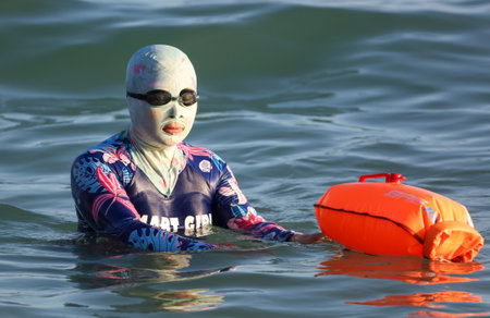 Sanya, Hainan Island, China - January 8, 2020: Woman with a closed face on the beach in Dadonghai Bay.のeditorial素材