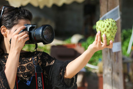 Sanya, Hainan Island, China - January 8, 2020: A girl photographs anon fruit on the beach in Dadonghai Bay.のeditorial素材