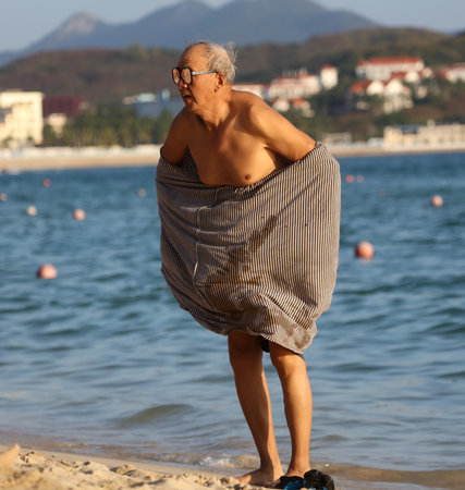 Sanya, Hainan Island, China - January 8, 2020: Old man on the beach in Dadonghai Bay.のeditorial素材