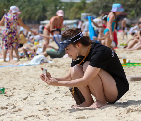 Sanya, Hainan Island, China - January 8, 2020: A girl photographs on the beach in Dadonghai Bay.のeditorial素材