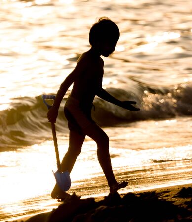 A boy plays in the sand on the seashore.の写真素材