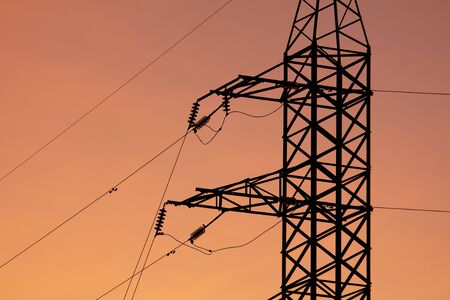 Electric pole with wires on a sunset background.