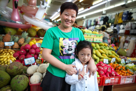 Sanya, Hainan Island, China - January 10, 2020: Portrait of a Chinese woman with a daughter near the fruit counter.のeditorial素材