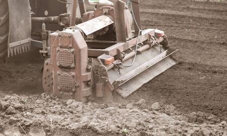 A tractor plows the land on nature in spring.の写真素材