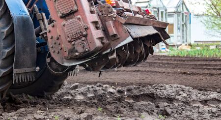 A tractor plows the land on nature in spring.の写真素材