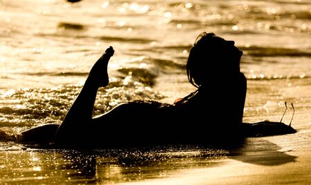 The girl lies on the seashore at sunset.の写真素材