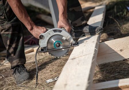 A worker saws a wooden beam. Building a house.の写真素材