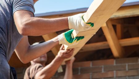 Worker holds a wooden board. Building a house.の写真素材
