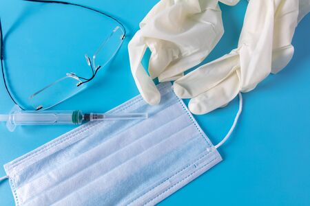 Medical mask, gloves, glasses and syringe isolated on a blue background.の写真素材
