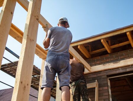 Worker holds a wooden board. Building a house.の写真素材