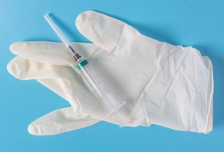 Medical gloves and syringe isolated on a blue background.の写真素材