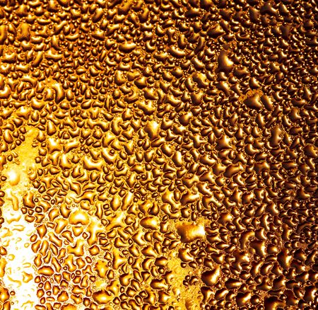 ÐÐ°Ð¿Ð»Ð¸ Ð²Ð¾Ð´Ñ Ð½Ð° ÑÑÐµÐºÐ»Ðµ Ð² Ð·Ð¾Ð»Ð¾ÑÑÑ Ð»ÑÑÐ°Ñ ÑÐ¾Ð»Ð½ÑÐ°. ÐÐ±ÑÑÑÐ°ÐºÑÐ½ÑÐ¹ ÑÐ¾Ð½.の写真素材