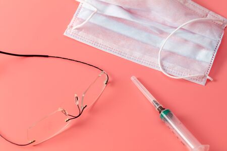 Mask, glasses and syringe isolated on a pink background.の写真素材