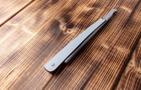 Dangerous razor for haircuts on a wooden background.