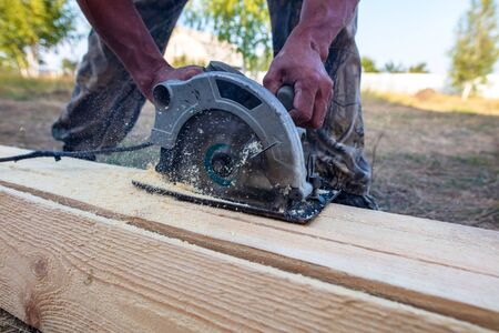 A worker saws a wooden beam. Building a house.の写真素材