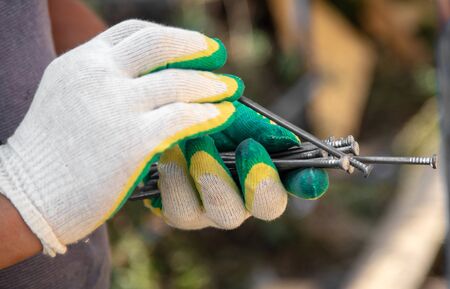 Nails in the hand of a worker. Building a house.